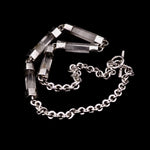 Close-up detail of handmade sterling silver and natural clear quartz crystal bar necklace, showing individual crystal bars set in hand-fabricated silver end caps, connected with jump rings, with handmade belcher chain visible, Thornhill Jewellery