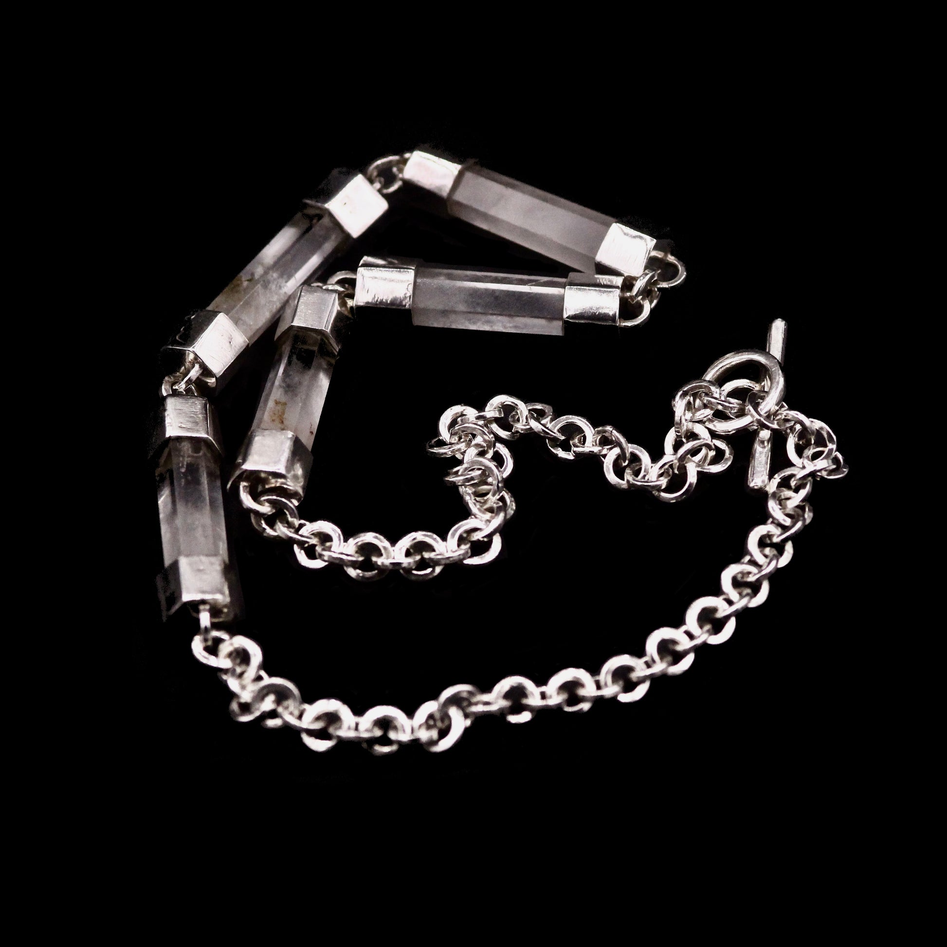 Close-up detail of handmade sterling silver and natural clear quartz crystal bar necklace, showing individual crystal bars set in hand-fabricated silver end caps, connected with jump rings, with handmade belcher chain visible, Thornhill Jewellery