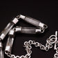 Handmade sterling silver and natural clear quartz crystal bar necklace coiled on black background, showing full length of crystal bar links transitioning into sterling silver belcher chain with T-bar toggle clasp, Thornhill Jewellery