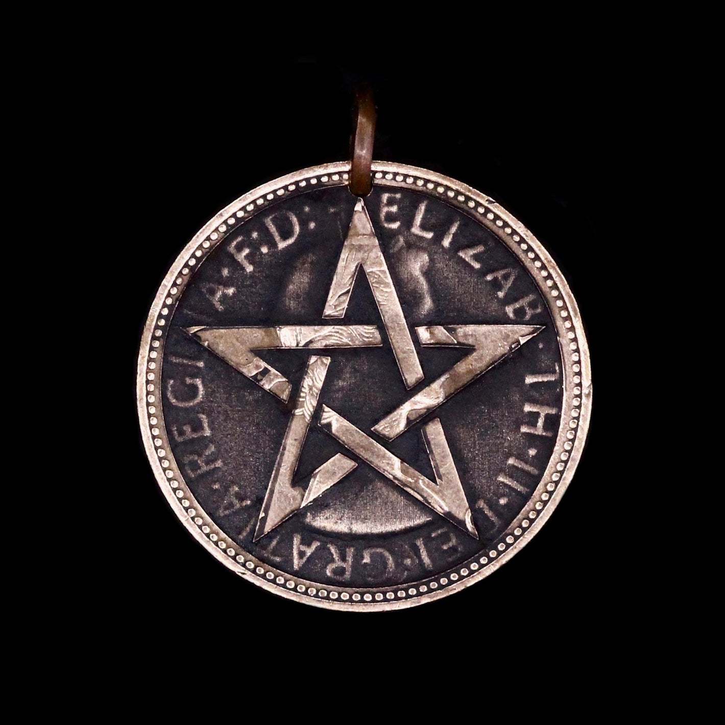Copper Penny coin pendant engraved with star on dark background, modern interpretation of trench art.